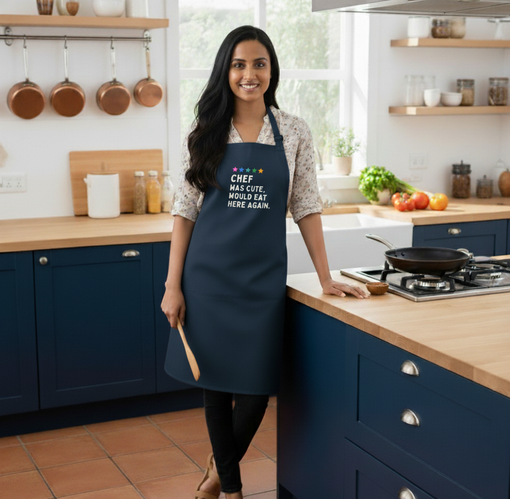 Woman wearing a navy apron with text in a kitchen
